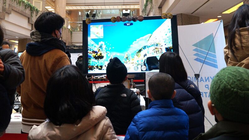 (写真)シューティングゲーム「Pointoon in みなとみらい」の前に並んで待つ子どもたち